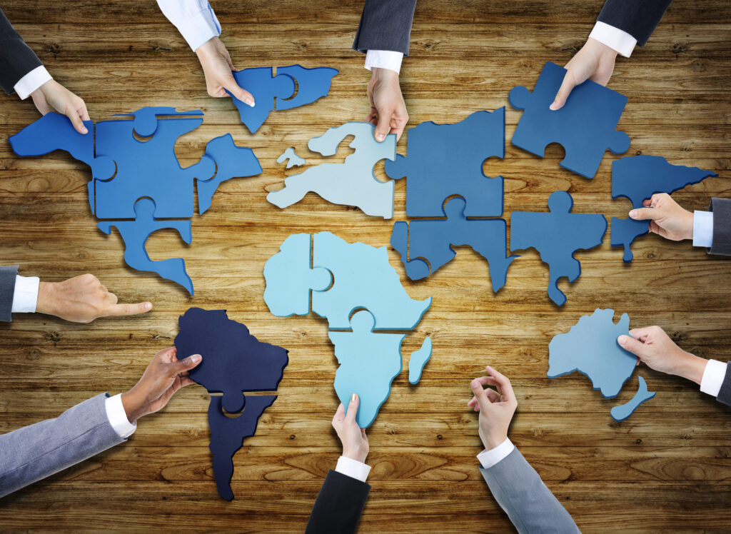 Group of Business People with Jigsaw Puzzle Forming in World Map
